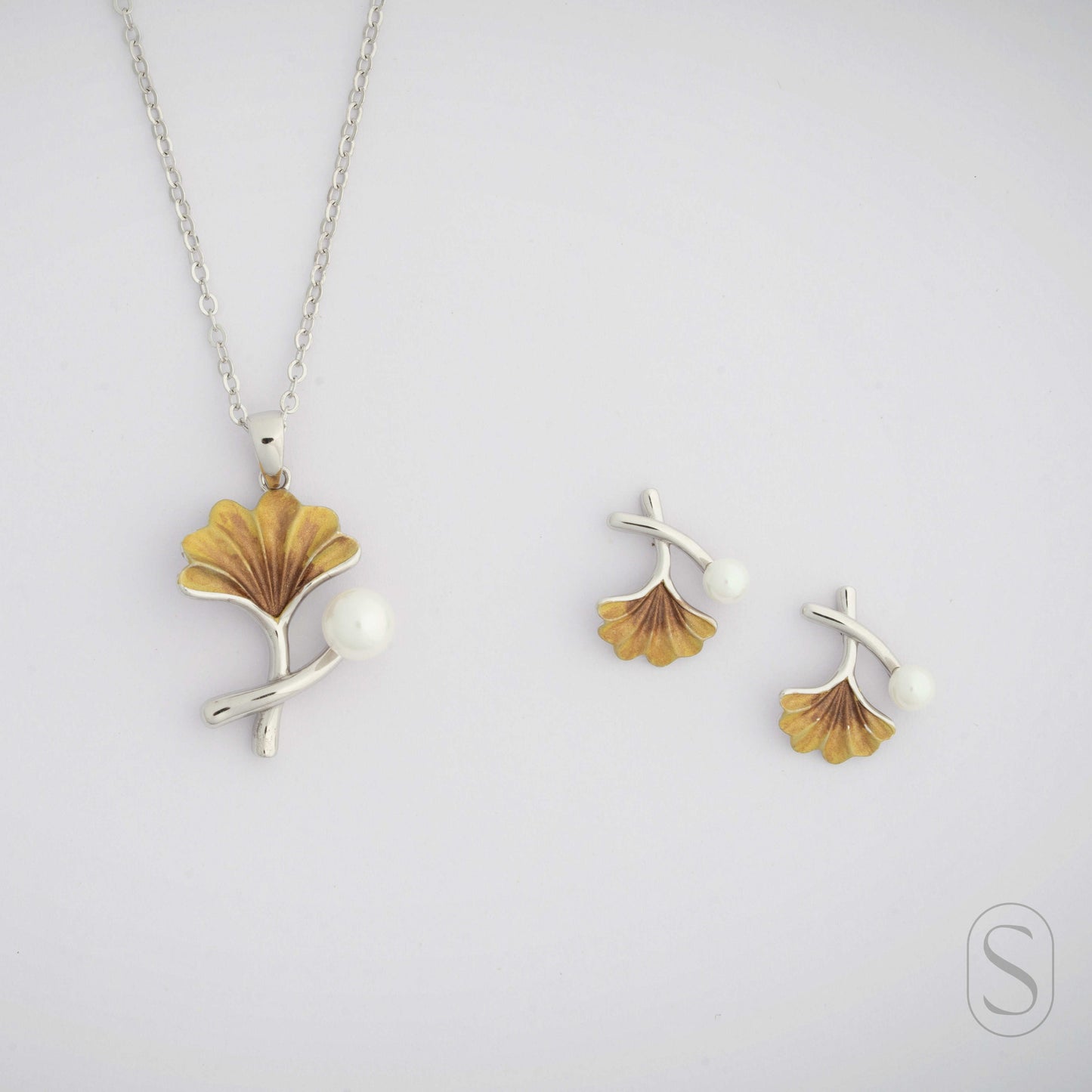 Jewelry set with a necklace and earrings featuring leaf designs on a light gray background by Silverlab