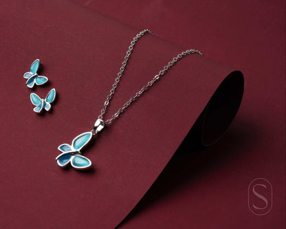 Butterfly necklace and earrings on a maroon background