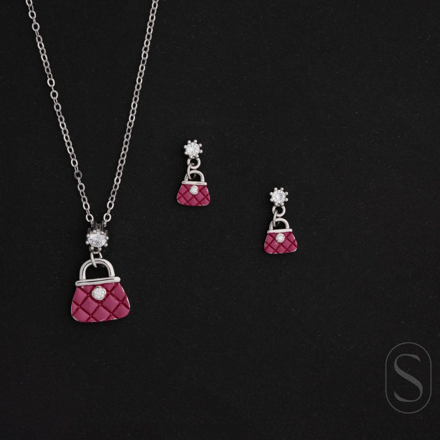 Jewelry set with pink purse-shaped pendant necklace and earrings on a black background