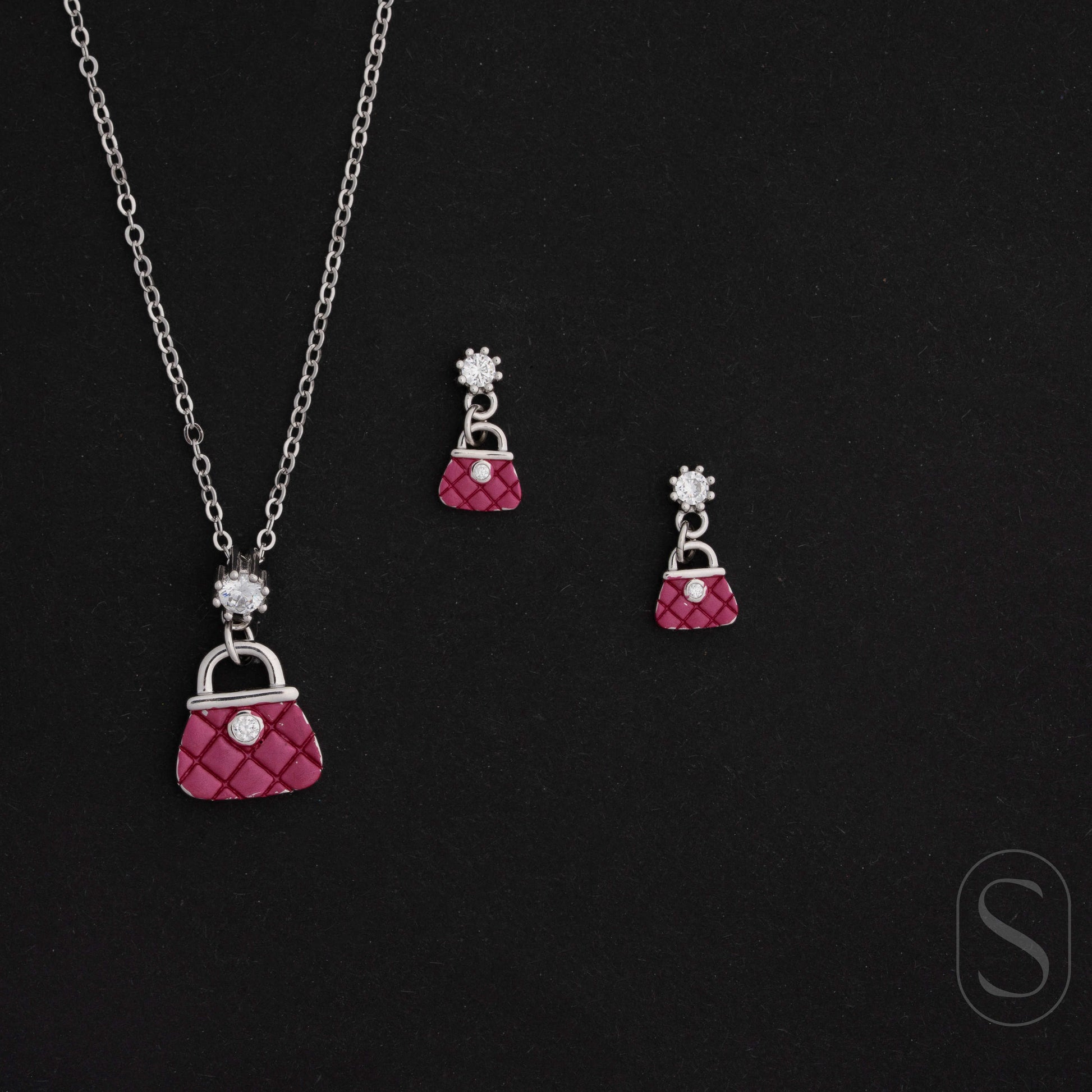 Jewelry set with pink purse-shaped pendant necklace and earrings on a black background