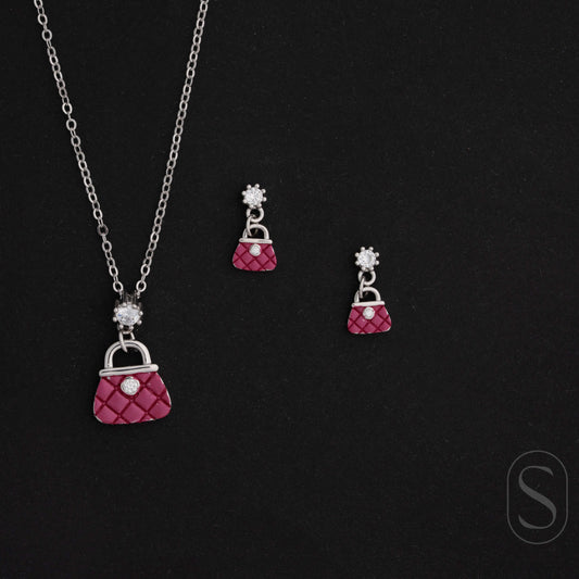 Jewelry set with pink purse-shaped pendant necklace and earrings on a black background